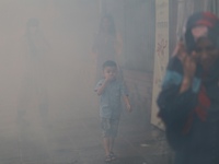 People walk on the street through smoke in Dhaka, Bangladesh on November 1, 2020.  (