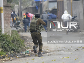 An Indian policeman chases Kashmiri protesters during clashes near encounter site in Rangreth area on the outskirts of Srinagar, Kashmir on...