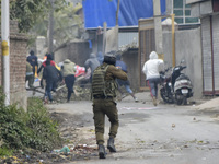 An Indian policeman chases Kashmiri protesters during clashes near encounter site in Rangreth area on the outskirts of Srinagar, Kashmir on...