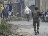 A Indian policeman chases Kashmiri protesters during clashes near encounter site in Rangreth area on the outskirts of Srinagar, Kashmir on 0...