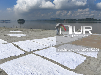 A Dhobi (washerman) dry bed sheets in the banks of Brahmaputra river, in Guwahati, India on 02 November 2020.  (