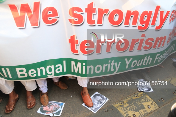 Supporters of All Bengal Minority Youth Federation demonstrators shout slogans and Protesters walk over posters of French President Emmanuel...