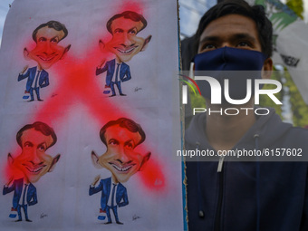 An activist from the Indonesia Muslim Student Action Unit (KAMMI) Palu carries a poster of French President Emmanuel Macron during a demonst...