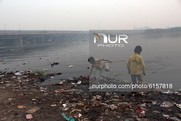 Children search for recyclable items near Yamuna river amid a layer of smoky haze, as the air quality of the national capital hit 'very poor...