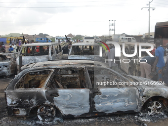 People stand next to burned cars after a tanker exploded on Lagos-Ibadan Expressway on November 7, 2020 in Ogun state killing two people in...