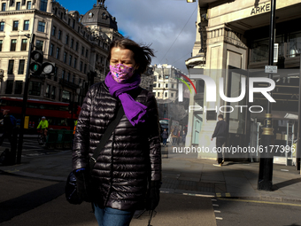 People wear mask as they walk along Regent Street, in London on November 2, 2020. (