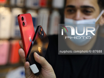 A Palestinian man holds Apple's new iPhone 12 at a mobile phone store in Gaza City on November 14, 2020. Apple's new iPhone 12 is selling we...