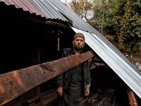 Noor Mohammad repairs the rooftop of his house which was damaged due to massive border shelling in Balkote area of Hajipir in Uri sector, of...