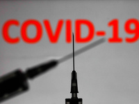Medical syringes are seen with ' COVID-19 ' sign displayed on a screen in the background in this illustration photo taken in Poland on Novem...