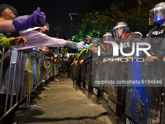 Pro-democracy protesters give water to riot police during a rally outside the Parliament in Bangkok to call for the ouster of Prime Minister...