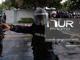 A riot police wear gas masks and anti-riot gear stand guard during a rally outside the Parliament in Bangkok to call for the ouster of Prime...