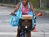 A woman on a bicycle carries food donated by the Second Harvest Food Bank of Central Florida and the City of Orlando at a food distribution...