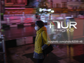 An Iranian woman wearing a protective face mask walks along an avenue at night which is empty of vehicles as the Capital city is in lockdown...