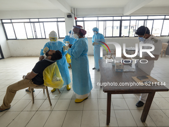 A Health worker in a protective suit  takes a throat swab of a man for a COVID-19 test as other health officials assist at Colombo, Sri Lank...