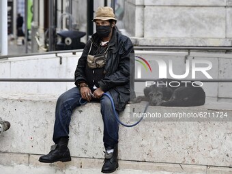 A man wearing a protective mask sits next to his pet in Chiado district, Lisbon. November 23, 2020. Portugal has recorded 4,788 new coronavi...
