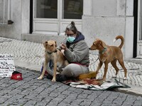 A woman wearing a protective mask sits with her pets in Chiado district, Lisbon.  November 23, 2020. Portugal has recorded 4,788 new coronav...