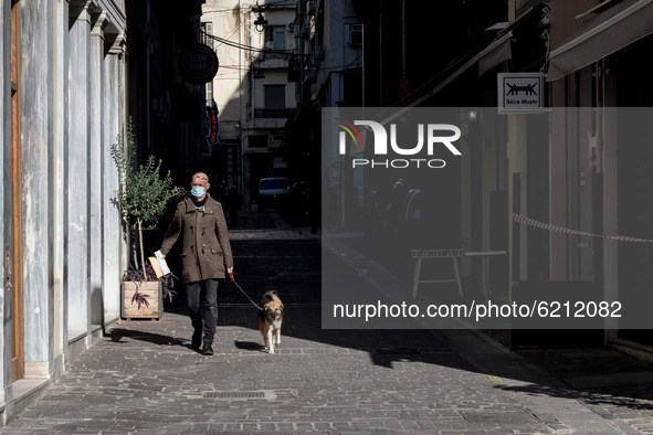 A man with protected mask and with his dog seen walking on an empty street in Athens, Greece on November 23, 2020 during the second COVID-19...