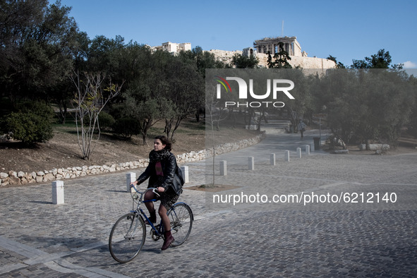 A woman seen riding her bicycle at the Acropolis heel with Acropolis from behind her in Athens, Greece on November 23, 2020 during the secon...