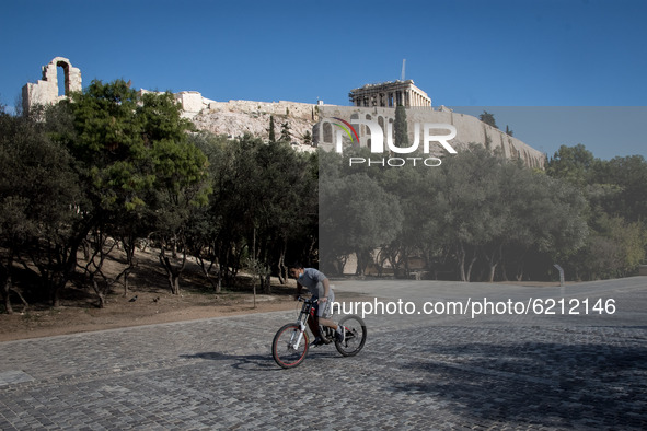 A man seen riding his bicycle at the Acropolis heel with Acropolis from behind him in Athens, Greece on November 23, 2020 during the second...