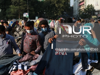 People buy winter clothes from a street vendor amid the COVID-19 coronavirus pandemic in Dhaka, Bangladeah on November 23, 2020. (