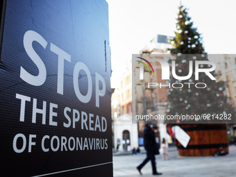 A coronavirus warning sign stands near a Christmas tree outside Covent Garden covered market in London, England, on November 23, 2020. Acros...
