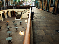 The empty tables of a temporarily closed restaurant stand in the lower courtyard of a near-deserted Covent Garden covered market in London,...