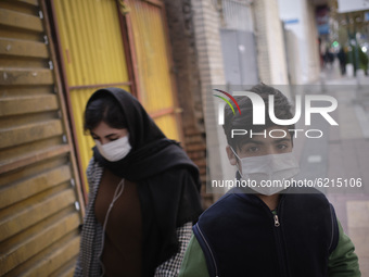 An Iranian boy wearing a protective face mask looks on as he poses for a photograph on a street-side in northern Tehran on day-3 of two-week...