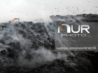 Excavators working to containing smouldering fire by dispersing garbage after a fire broke out at east Delhi's Ghazipur landfill in New Delh...