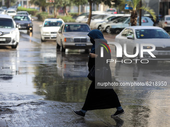 A Palestinian woman walks through a street flooded with rain water  during a rainy day in Gaza City on November 26, 2020. 
 (
