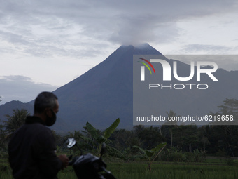 Local residents do activities on the slopes of Merapi mountain as the solfatara smoke spews from the top of Merapi volcano as seen from Yogy...