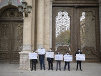 Protesters hold placards while attending a protest gathering against the assassination of the Iranian Top nuclear scientist and a member of...