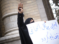A female veiled protester gestures as she holds a placard with a Persian script that said, Implement the NPT must be stope, during a protest...
