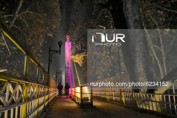 People walk on a illuminated bridge during cold winter evening in Srinagar, Indian Administered Kashmir on 30 November 2020. 