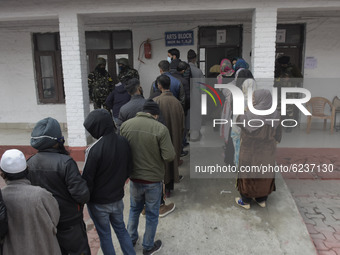 Indian forces stand alert as people stand in line outside a voting booth duirng second phase of DDC, ULP elections in Srinagar, Indian Admin...