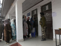 Indian forces stand alert as people stand in line outside a voting booth duirng second phase of DDC, ULP elections in Srinagar, Indian Admin...