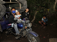 A family from Sumbersari village take a rest on their three-wheeled motorbike in Supiturang village after being evacuated on December 2, 202...