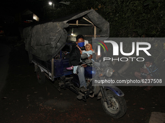 A family from Sumbersari village take a rest on their three-wheeled motorbike in Supiturang village after being evacuated on December 2, 202...