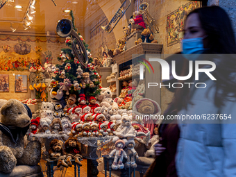 Passers-by in protective face masks  are seen by a shop window with Christmas decorations on a cold winter evening on Florianska Street by t...