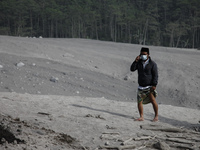 Villagers of Curah Kobokan receive a phone call as he walks on the Besuk Kobokan river which full of volcanic materials fom the eruption of...