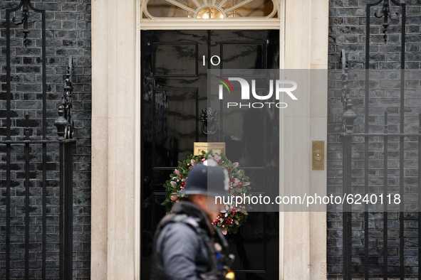 A police officer walks past the door of 10 Downing Street, on which now hangs a Christmas wreath for the festive season, in London, England,...