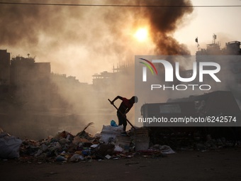 A labour works at a garbage area as fire creates toxic smoke at Keraniganj area in Dhaka, Bangladesh on Thursday, December 03, 2020. (