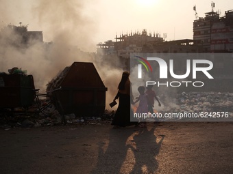 People make their move as garbage fire creates toxic smoke besides a road at Keraniganj area in Dhaka, Bangladesh on Thursday, December 03,...