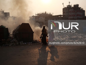 People make their move as garbage fire creates toxic smoke besides a road at Keraniganj area in Dhaka, Bangladesh on Thursday, December 03,...