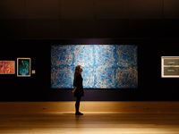 A member of staff wearing a face mask poses in front of oil and screenprint on canvas work 'Blue Computergram', by British artist Brian Clar...