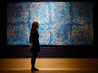 A member of staff wearing a face mask poses with oil and screenprint on canvas work 'Blue Computergram', by British artist Brian Clarke, est...