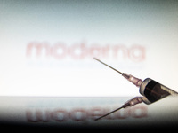 Photo illustration of a medical syringe with a needle seen in front of the Moderna pharmaceutical corporation logo. Moderna expects the Amer...