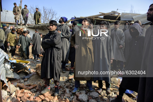 Kashmiri people stand on the debris of a damaged residential house in Kanigam Village of Shopian district, South of Srinagar, Indian Adminis...
