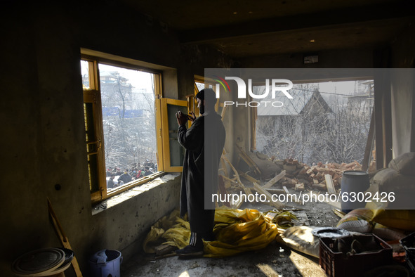 A Kashmiri man clicks picture inside a damaged residential house in Kanigam Village of Shopian district, South of Srinagar, Indian Administe...