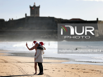 A couple wearing Santa Claus hats kisses during a traditional sea bath to welcome the new year at Carcavelos beach on the outskirts of Lisbo...