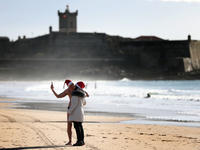 A couple wearing Santa Claus hats kisses during a traditional sea bath to welcome the new year at Carcavelos beach on the outskirts of Lisbo...